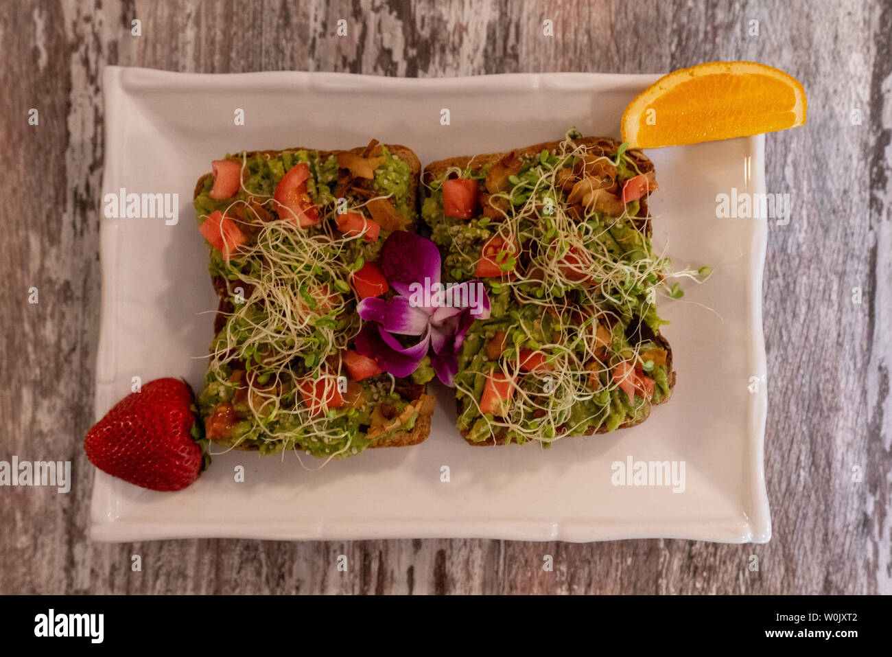 Sandwichs sains aliments complets avec garniture de salade aux pousses, la tomate et la laitue sur une assiette garnie de tranches de fraise et orange Banque D'Images