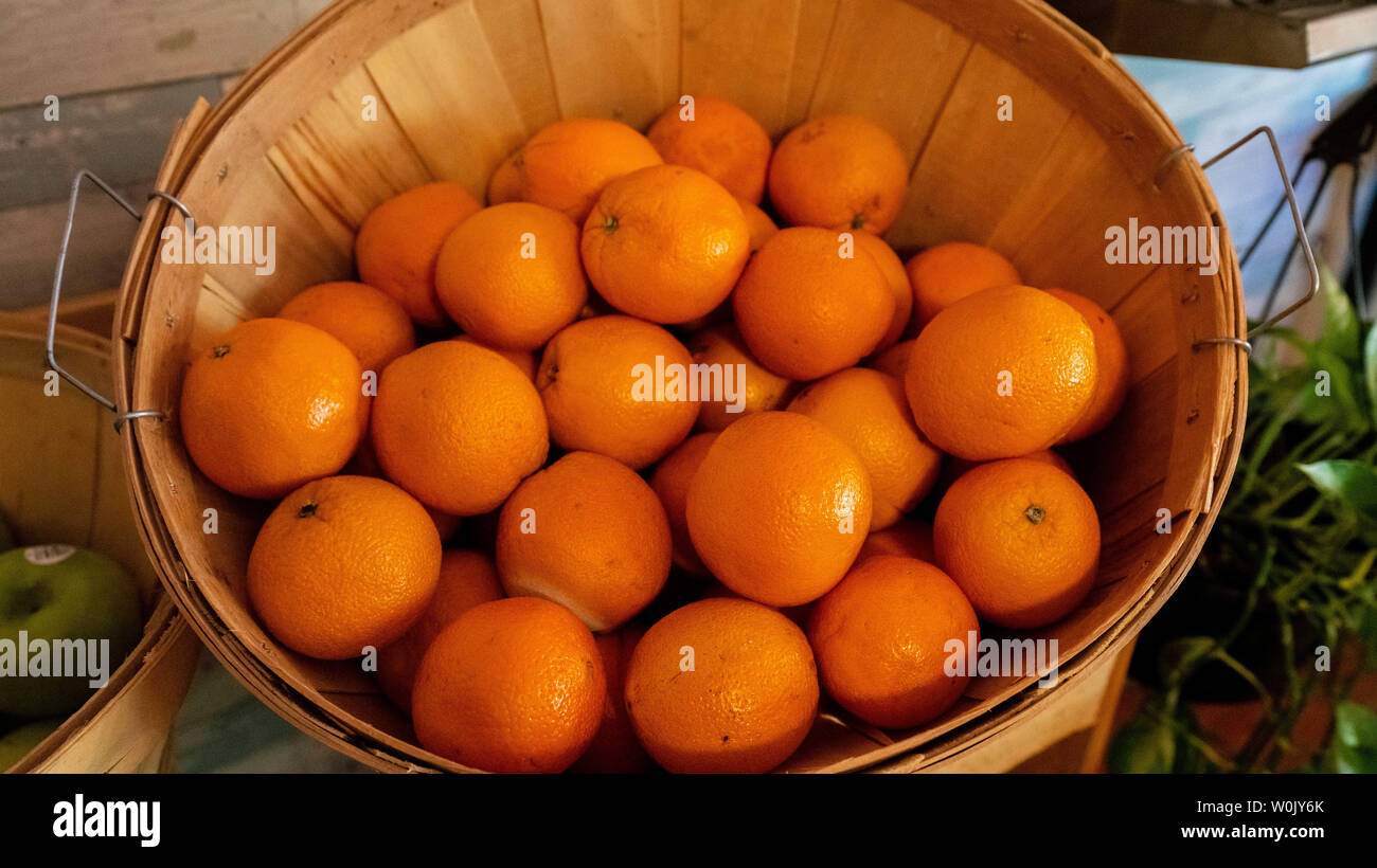 Panier en rotin rempli d'agrumes frais sur un buffet ou table du marché aux côtés de la pomme verte dans un close up high angle view Banque D'Images