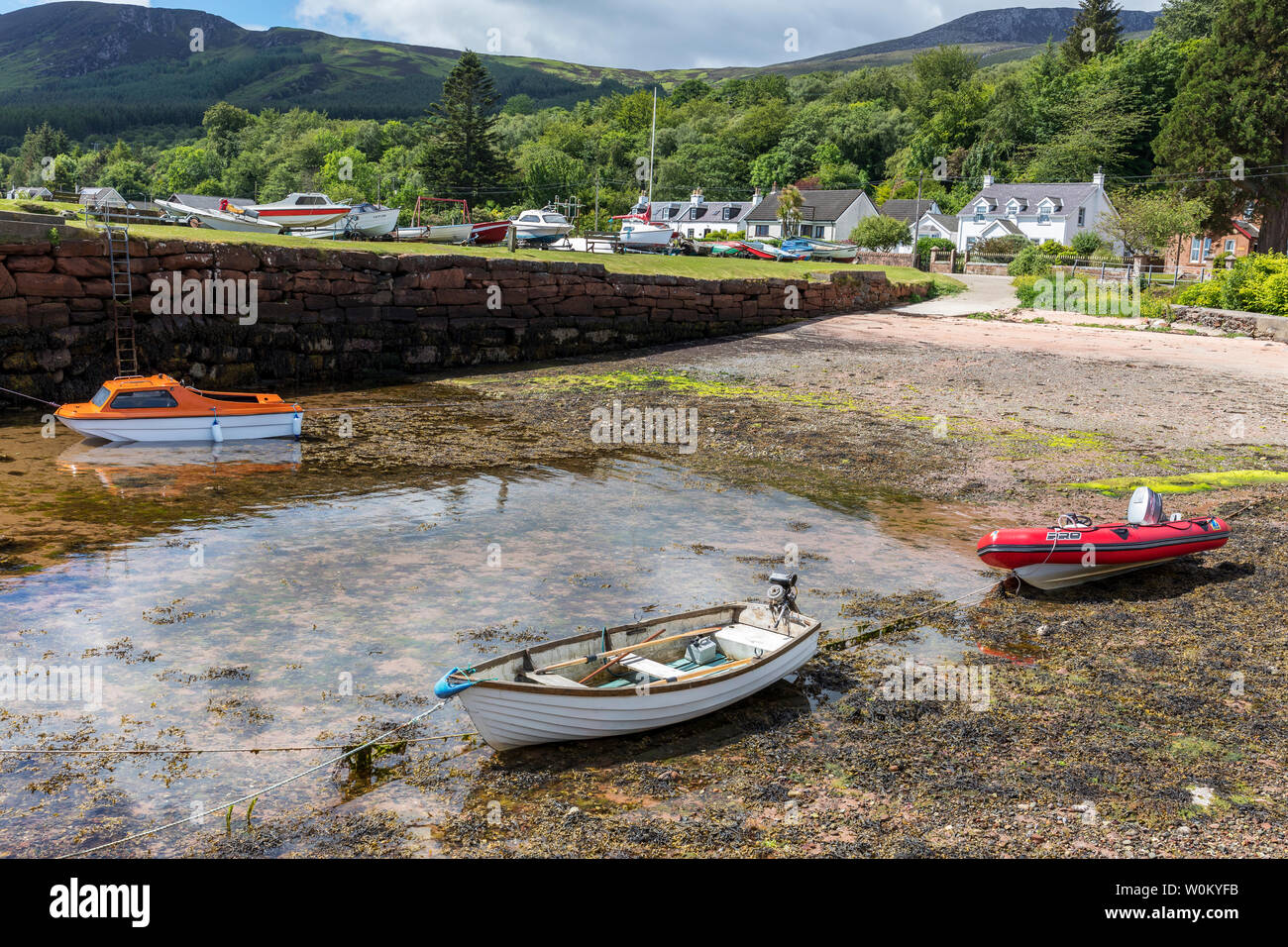 Petit port à Corrie sur l'île d'Arran, Firth of Clyde, en Écosse avec trois petits bateaux au bord de l'eau. Banque D'Images