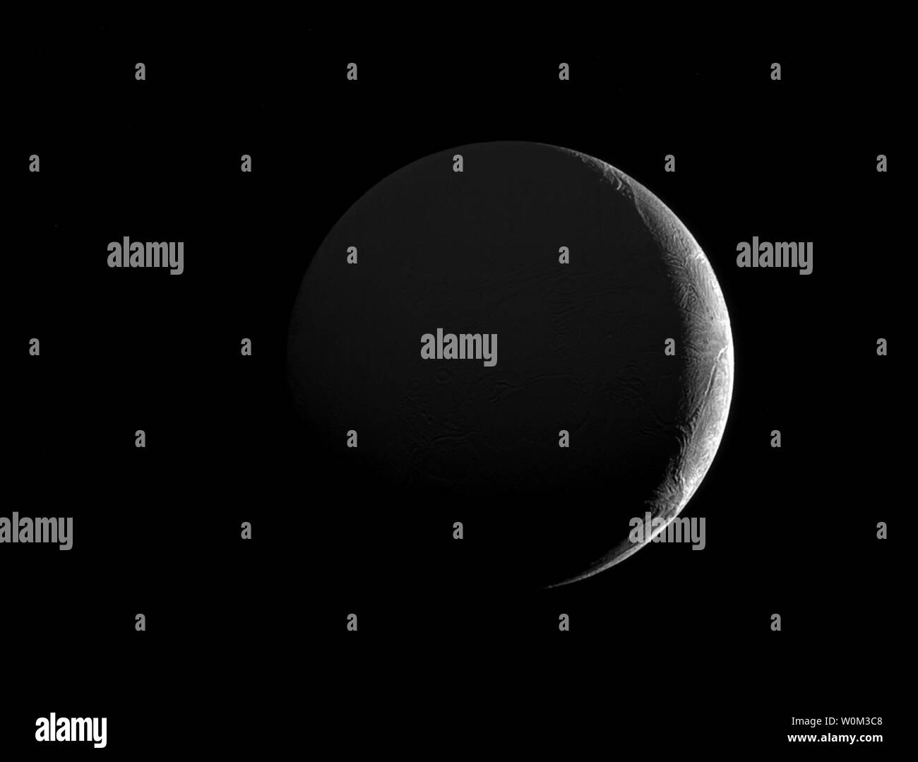 Le faible angle de la lumière du soleil le long de la mince croissant de la lune de Saturne Encelade (313 milles ou 504 kilomètres) met en lumière les nombreuses fractures et de sillons sur sa surface glacée. Cette vue se tourne vers l'hémisphère face à Saturne d'Encelade, qui est allumé faiblement dans l'image ci-dessus par la lumière du soleil réfléchie sur Saturne. Au nord sur Encelade est tourné vers le haut et 14 degrés vers la gauche. L'image a été prise en lumière visible avec la sonde Cassini caméra à angle étroit, le 26 décembre 2016. NASA/UPI Banque D'Images
