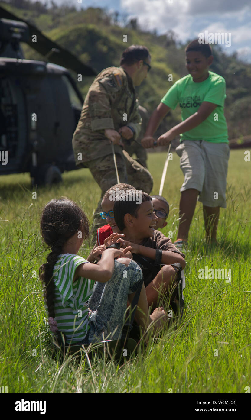 Le sergent de l'armée américaine. Ryan P. Hinojosa (arrière gauche), affecté à la 101e Brigade d'aviation de combat (cabine), 101st Airborne Division (Air Assault), tire sur un groupe d'enfants sur une litière, Jayuga, Porto Rico, le 4 octobre 2017. La 101e CAB mène des efforts de secours et d'évacuation médicale à l'appui de la FEMA dans le processus de récupération de Puerto Rico après la dévastation créée par l'Ouragan Maria. Photo prise par le s.. Pablo Piedra/U.S. Army/UPI Banque D'Images