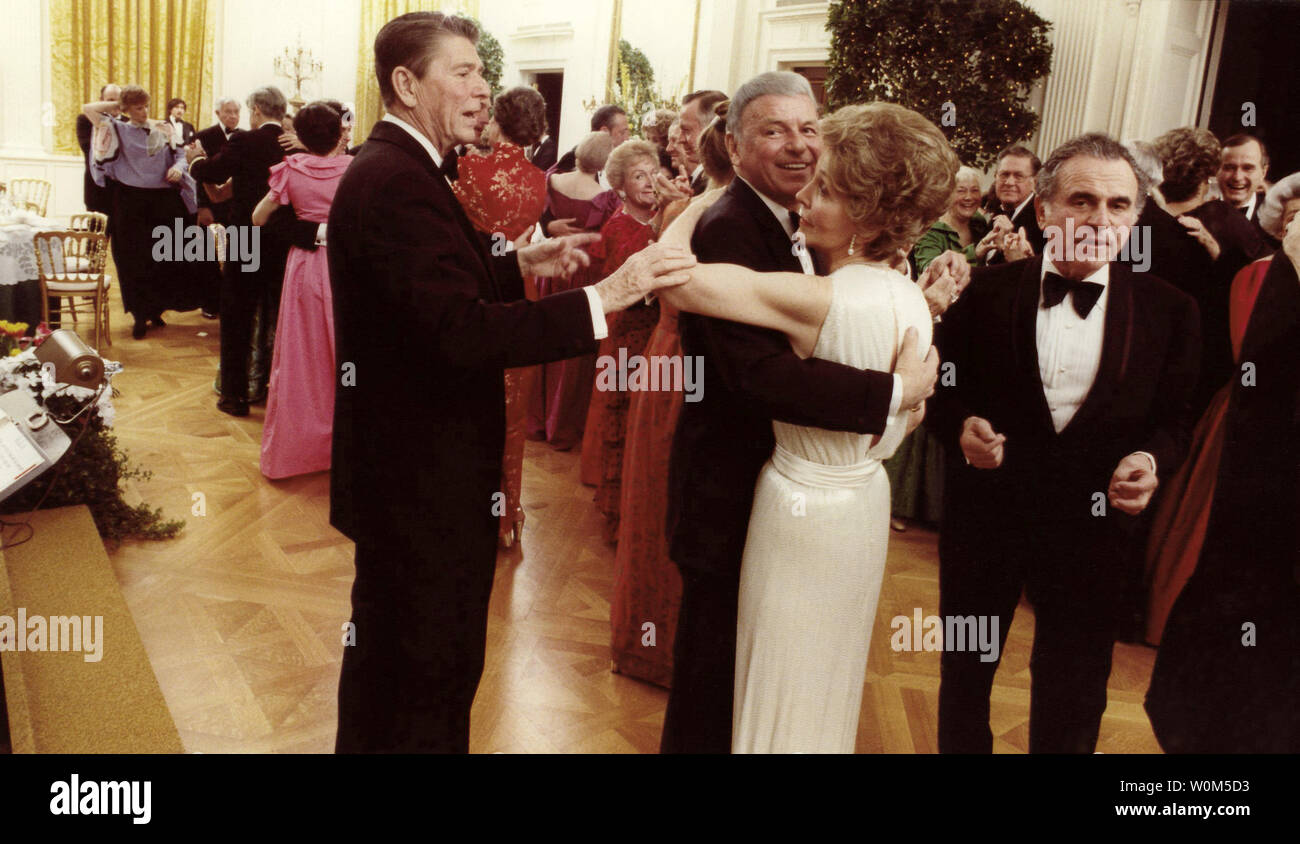 Le président Ronald Reagan est vu ici dans ce 6 février 1981 Photo de la coupe dans le Frank Sinatra et Nancy Reagan à la présidence d'anniversaire à la Maison Blanche. À la droite est directeur de l'ICA Charles Wick. (UPI/fichier) Banque D'Images