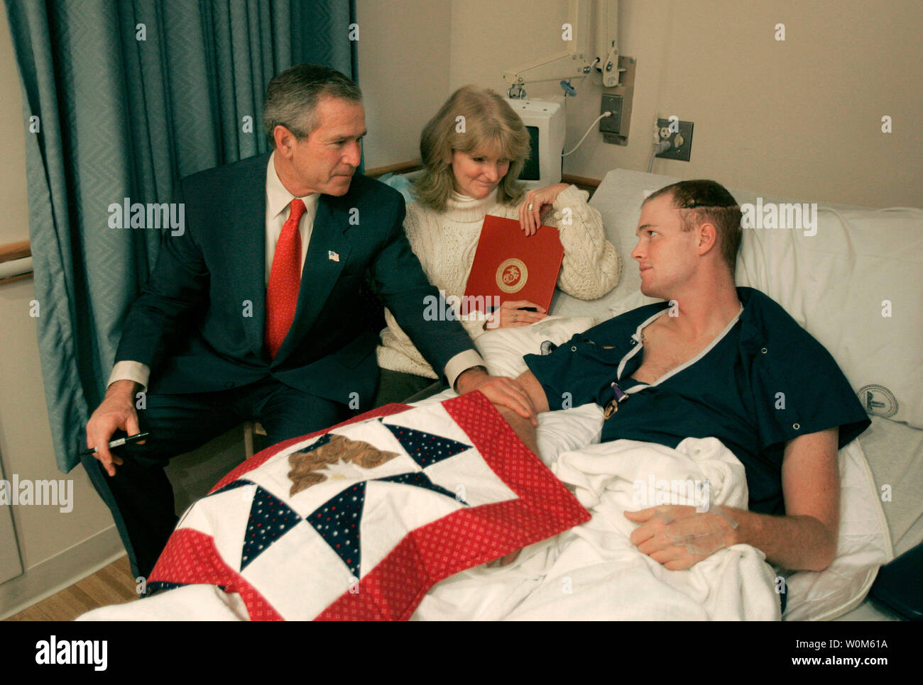 Le Président George Bush des visites avec l'USMC Lance Corporal Sean Phillips et sa mère, Sharon, au National Naval Medical Center de Bethesda, MD, le 11 décembre 2004. Le Cpl. Phillips a été blessé en Irak. Lors de la récupération à l'Allemagne, il a reçu un don de la part de partisans de courtepointe au Texas. Le Président a ajouté ses propres Texas signature à la courtepointe. (UPI Photo/Paul Morse/maison blanche) Banque D'Images