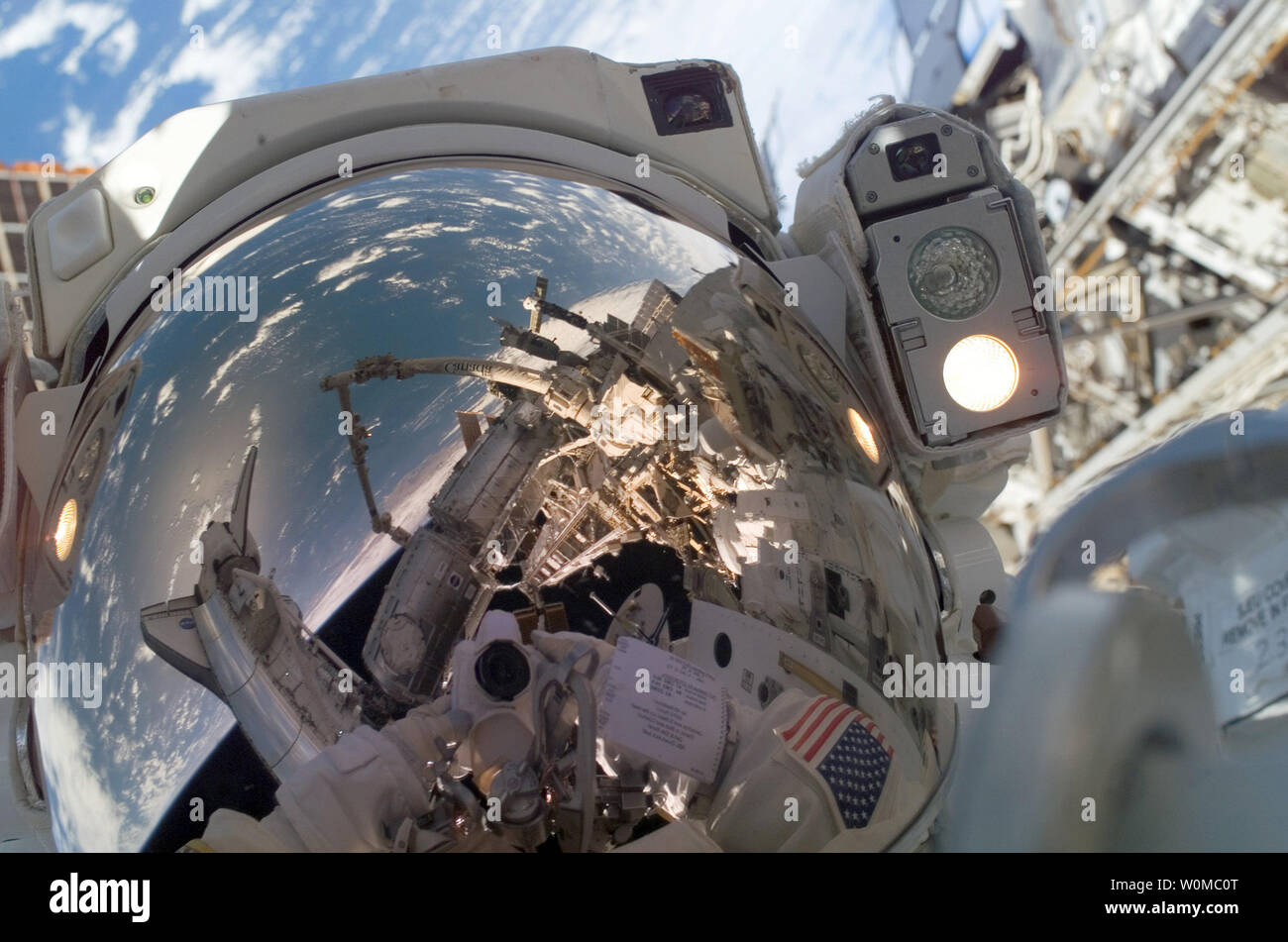 L'astronaute de l'ingénieur de vol de l'expédition 16 Garrett Reisman utilise un appareil photo numérique d'exposer une photo de son casque pare-soleil au cours de la première session de la mission prévue de l'activité extravéhiculaire (EVA) à la Station spatiale internationale le 14 mars 2008. Également visible dans les reflets dans le pare-soleil sont diverses composantes de la station, la navette spatiale Endeavour amarrée bleu et blanc et une partie de la Terre. Durant les sept heures et d'une minute, sortie dans l'Reisman et spécialiste de mission STS-123 L'astronaute Rick Linnehan (hors cadre) a préparé le module logistique japonais-section sous pression (PAM) pour Banque D'Images