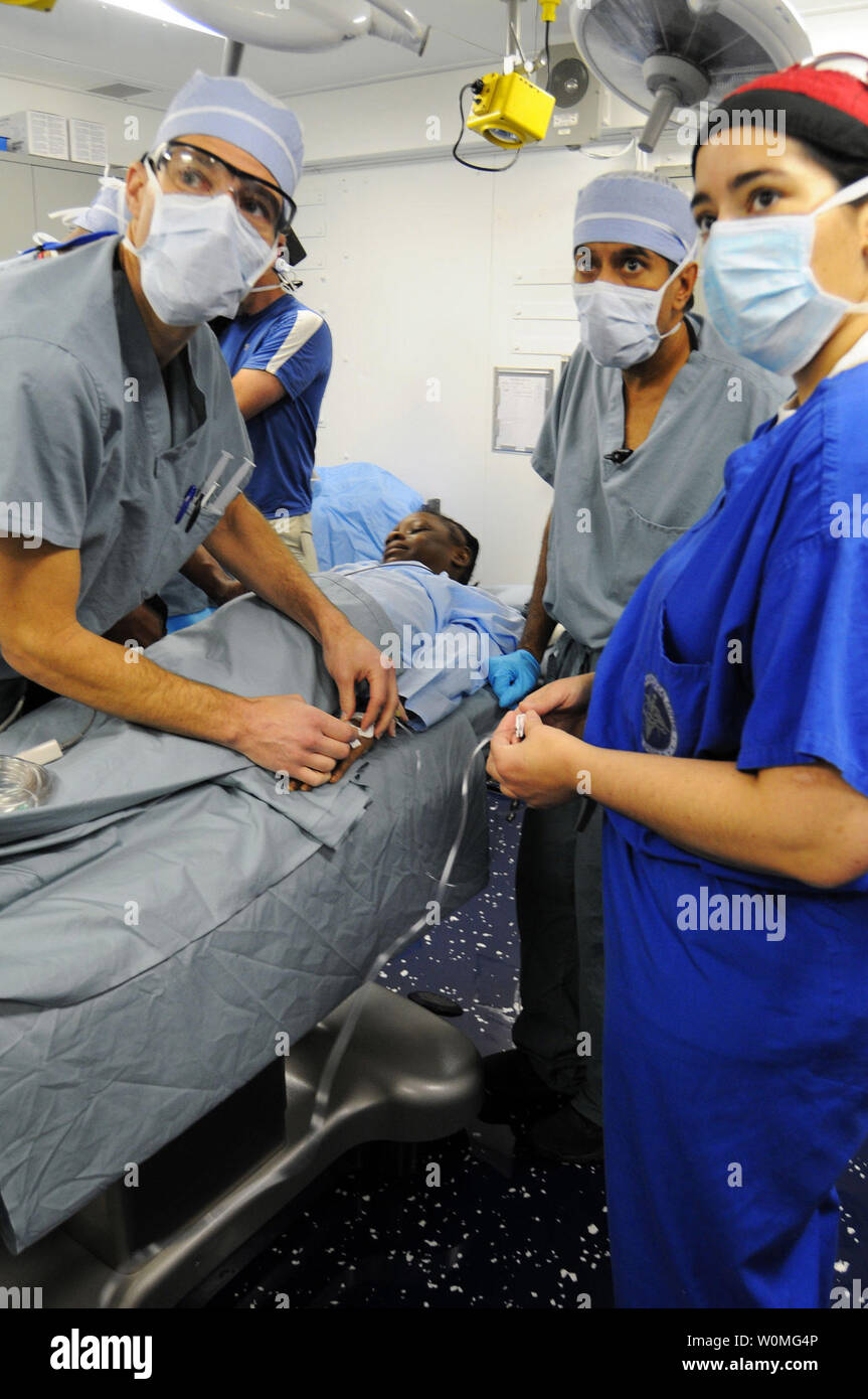 Le cmdr. Jerry Berman, gauche, un chirurgien de la Marine, le Dr Henri R. Ford, Los Angles Hôpital Pédiatrique chirurgien en chef originaire d'Haïti, le Dr Sanjay Gupta, un correspondant médical de CNN et la pratique, le neurochirurgien et le lieutenant Cmdr. Kathryn Berndt, un chirurgien de la Marine, préparer un 12-year-old fille haïtienne avec une grave blessure à la tête pour la chirurgie à bord du porte-avions de classe Nimitz USS Carl Vinson (CVN 70) près de Port-au-Prince, Haïti, le 18 janvier 2010. Chirurgiens enlevé un morceau de béton du cerveau de l'enfant provoquée par le tremblement de terre en Haïti. Michael Barton/UPI/U.S. Navy Banque D'Images