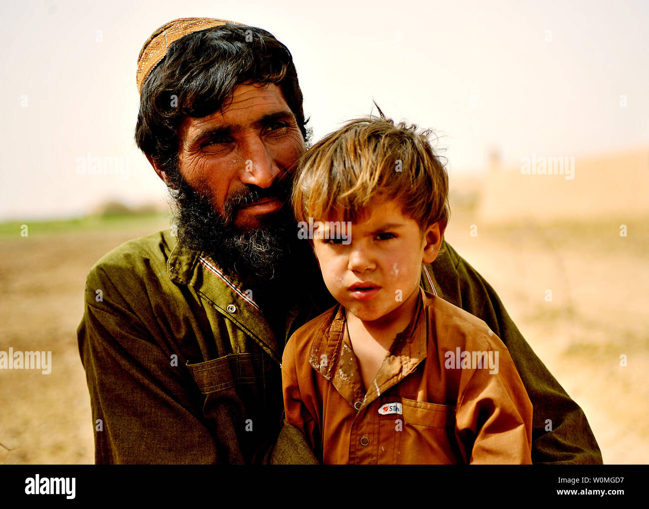 Un homme afghan et son garçon assis sur le sol tandis que les anciens du village de Tamir, Farah Provence, l'Afghanistan s'entretenir avec la direction de l'Armée nationale afghane à propos des améliorations pour le village, le 28 février 2010. UPI/Nicholas Pilch/U.S. Air Force. Banque D'Images