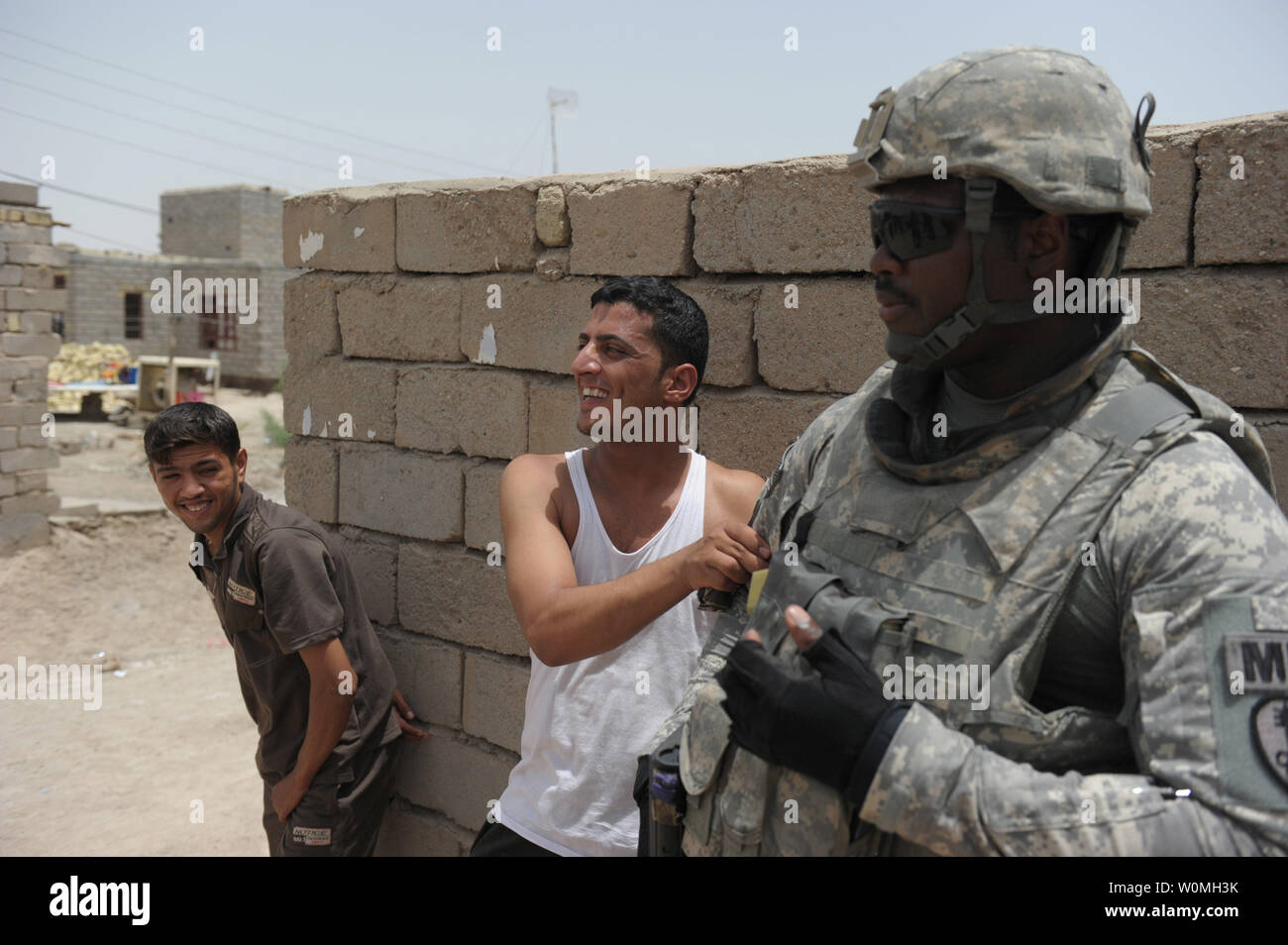 Le sergent de l'armée américaine. Brandon Moton, avec 354e Compagnie de Police Militaire, 1er Bataillon, 68e régiment de blindés, 3e Brigade, 4e Division d'infanterie, pose avec les civils irakiens près de la base d'opérations d'urgence à Bassorah, Irak, le 15 juillet 2010. UPI/Jason A. Young/US ARMY Banque D'Images