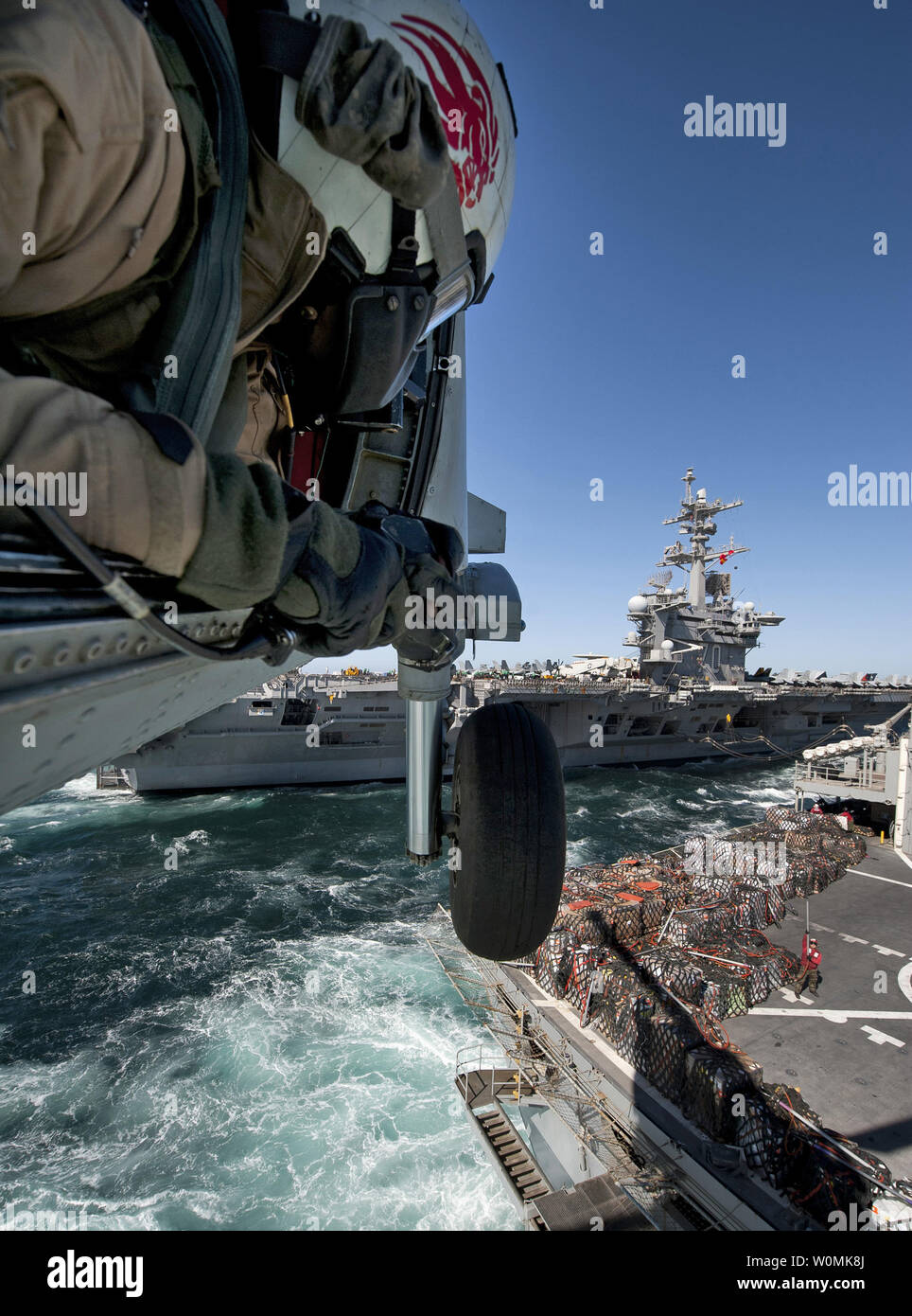 U.S. Navy Naval Air Crewman 2e classe Cory Merritt, affecté à l'Escadron d'hélicoptères anti-sous-marin (HS) 15 guides, les pilotes d'un HH-60H Seahawk hélicoptère comme ils récupérer la cargaison de l'appui au combat rapide USNS Bridge navire au cours d'un ravitaillement en mer avec le porte-avions USS Carl Vinson dans le golfe Persique le 6 mars 2012. Carl Vinson et Carrier Air Wing 17 ont été déployées pour la 5e Flotte des États-Unis zone de responsabilité. James R. Evans/UPI/U.S. Navy Banque D'Images