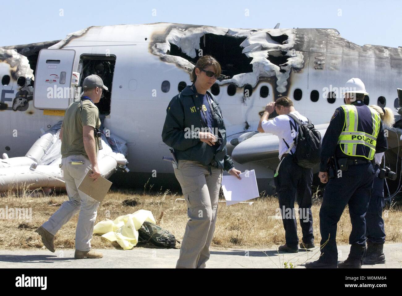 Dans cette photo fournie par le National Transportation Safety Board, NTSB enquêteurs inspecter les lieux de l'accident de vol Asiana 214 à San Francisco, Californie le 7 juillet 2013. Le Boeing 777 est en route de Shanghai avec une escale à Séoul, Corée du Sud, de l'exécution 291 passagers. Deux personnes sont mortes et plus de 180 ont été blessées. Lee Kang-kook pilote avait enregistré plus de 9 000 heures sur divers appareils, mais seulement 43 heures sur Boeing 777 et a été considérée comme toujours en formation sur cet appareil. UPI Banque D'Images