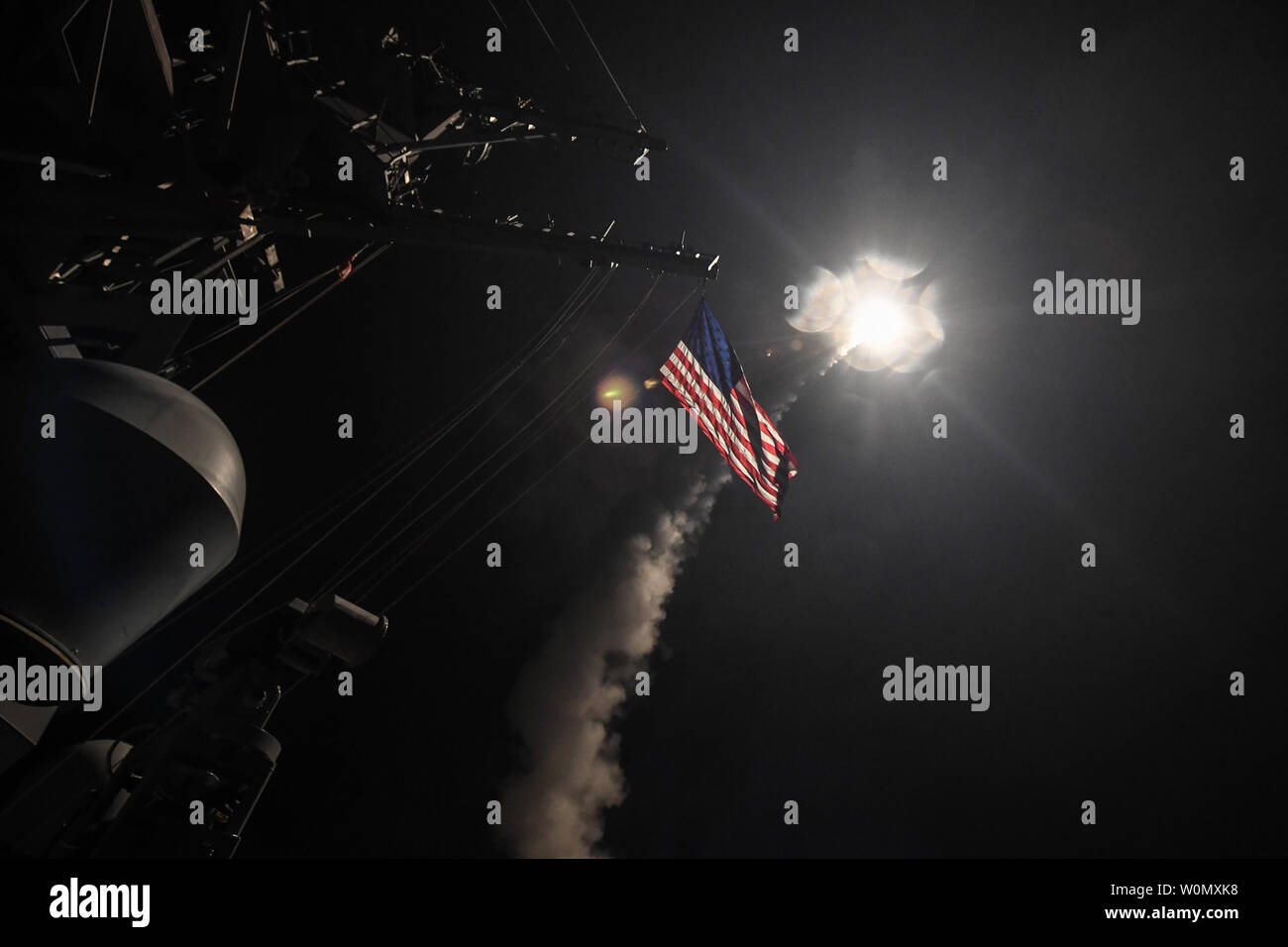 Un missile de croisière illumine le drapeau américain que le destroyer USS-missiles Porter (DDG 78) effectue des opérations de grève alors que dans la mer Méditerranée, le 7 avril 2017. Porter, l'avant-déployé à Rota, Espagne, mène des opérations navales dans la sixième flotte américaine zone d'opérations à l'appui de la sécurité nationale des États-Unis en Europe. Le président Donald Trump le jeudi soir a dit qu'il a ordonné 59 missiles de croisière pour attaquer l'aérodrome où le président syrien Bachar al-Assad's régime a lancé une attaque chimique mortel sur les civils deux jours plus tôt. U.S. Navy photo de classe 3ème MCS Ford vous Banque D'Images