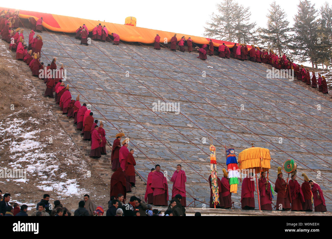 Moines tibétains se préparent à dévoiler une Thangka géant de bouddha, ou tapisserie, sur le flanc d'une montagne près du monastère de Labrang, le plus grand monastère tibétain à l'extérieur de Lhassa, au cours de la Tibetan Monlam Festival à Xiahe, une petite ville dans la province de Gansu, sur le plateau tibétain, le 4 février 2012. Milliers de moines tibétains, les pèlerins et les nomades ont convergé sur le monastère pour l'assemblée annuelle de l''Sxécutant Bouddha' rituel, dans lequel le plus grand Bouddha de Thangka (90m de longueur, 40 pieds de largeur) est présenté à la première lumière sur le flanc d'une montagne. Le Monlam festival, ou Festival de la grande prière, je Banque D'Images