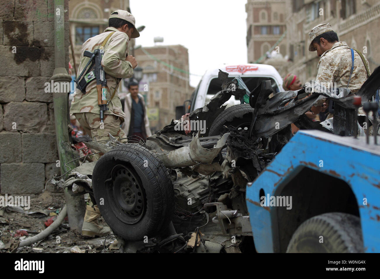 Combattants Houthi inspecter l'épave d'une voiture à l'emplacement d'une attaque près de Qubbat al-Mahdi mosquée de Sanaa, Yémen, le 20 juin 2015. Au moins trois personnes ont été tuées et sept autres personnes ont été blessées lorsqu'une voiture piégée a frappé une mosquée utilisé par le combattants Houthi dans la capitale du Yémen, selon des sources médicales... Photo par Mohammad Abdullah/UPI Banque D'Images