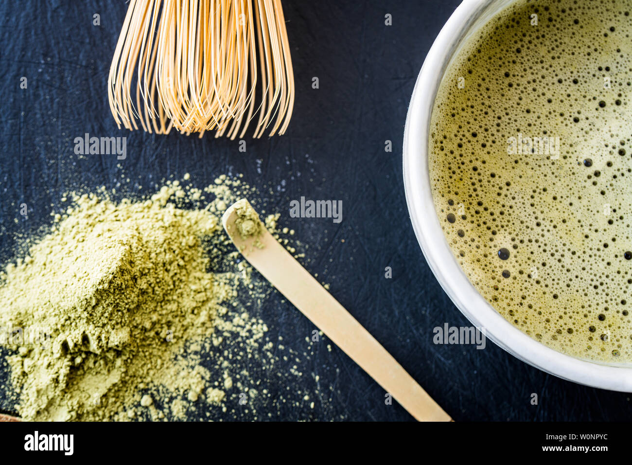 Un gros plan de thé vert matcha dans une tasse, cuillère bambou bambou whist, et le thé vert en poudre Banque D'Images