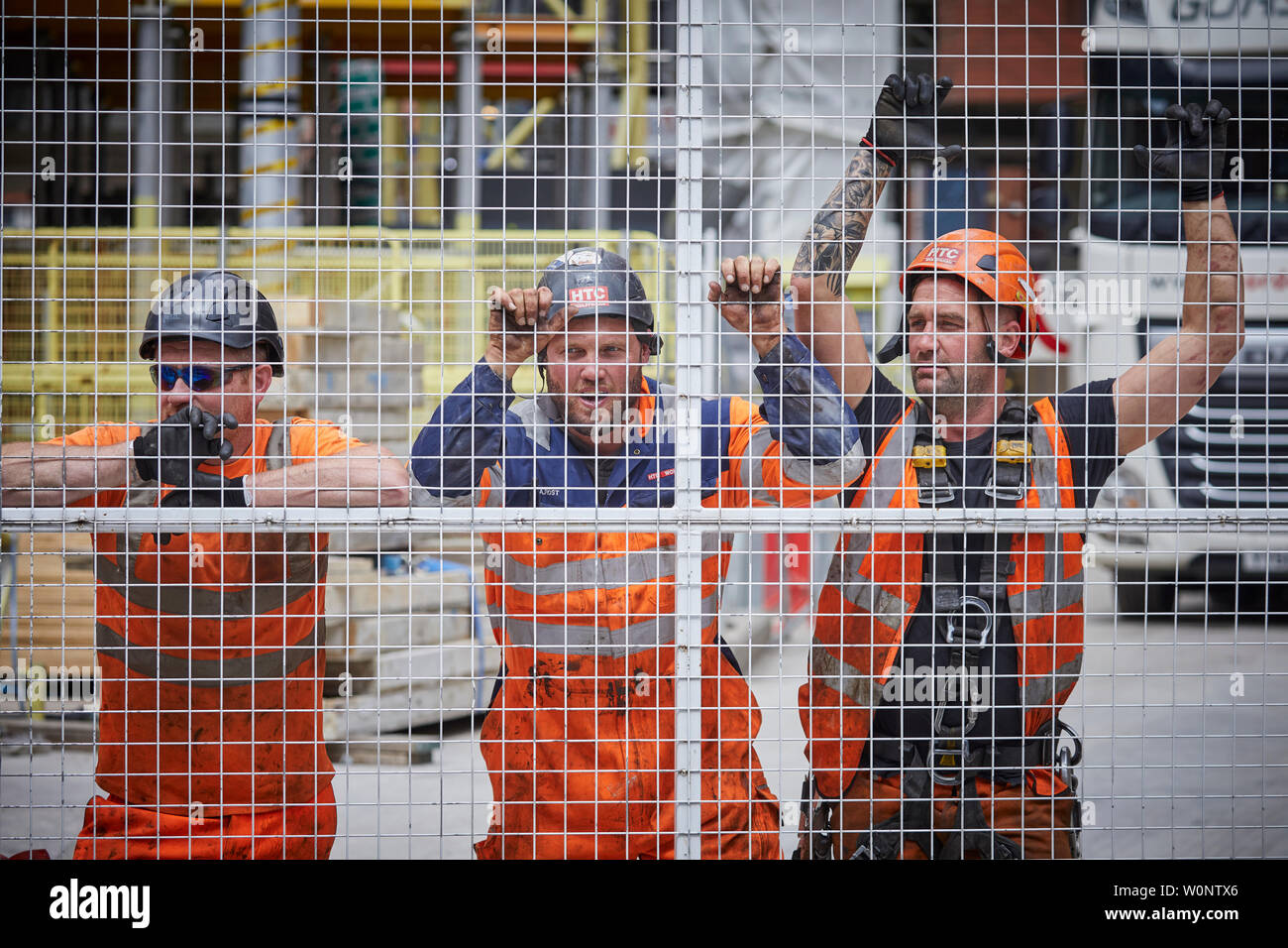 Le centre-ville de Manchester, des ouvriers prendre pause du travail à l'intérieur d'un site de construction, tourné à travers le grillage de métal gates Banque D'Images
