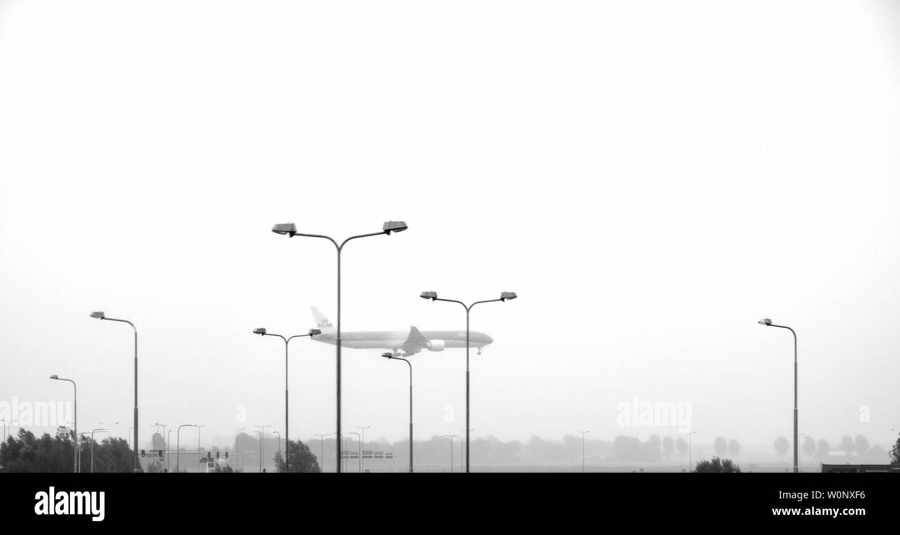 Amsterdam, Pays-Bas - Aug 19, 2018 : atterrissage avion KLM à Amsterdam Airport Schiphol sur un jour de pluie - low angle view image en noir et blanc Banque D'Images