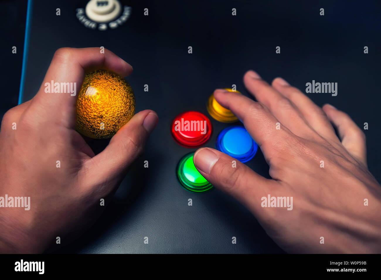 Arcade gamer tenant une bulle jaune top joystick et jouant sur un modèle à quatre boutons d'arcade. Banque D'Images