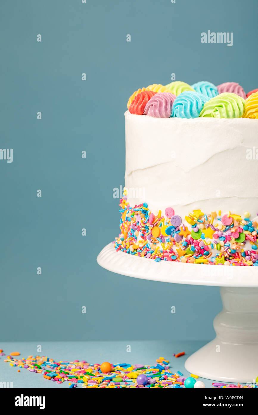 Gateau D Anniversaire Arc En Ciel Blanc Avec Degivrage Et Saupoudre Colores Sur Fond Bleu Photo Stock Alamy