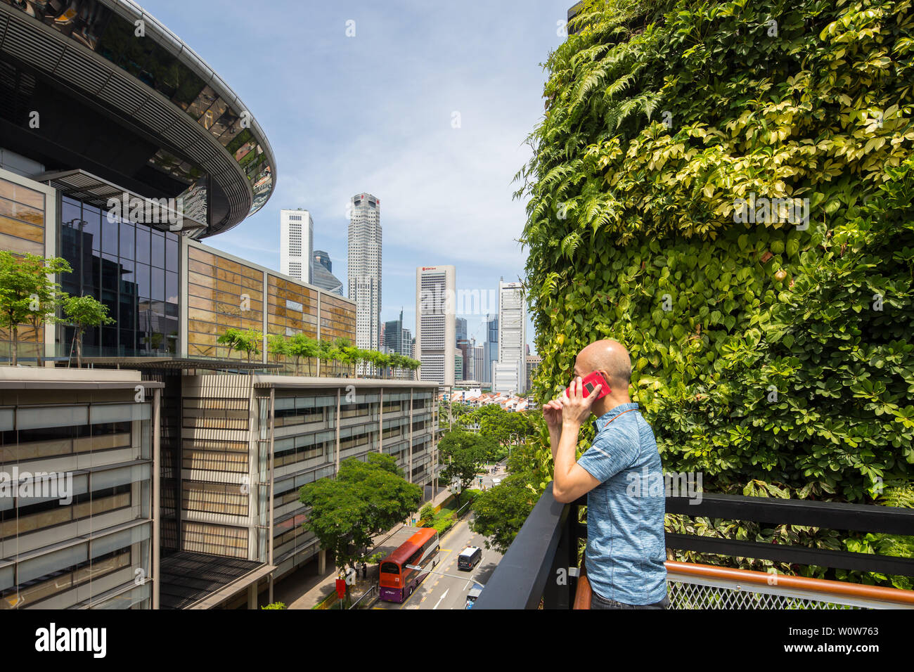 Un homme au téléphone à Urban Farming sur le toit du centre commercial Funan, le toit offre une vue sur la rue de la ville, Singapour Banque D'Images