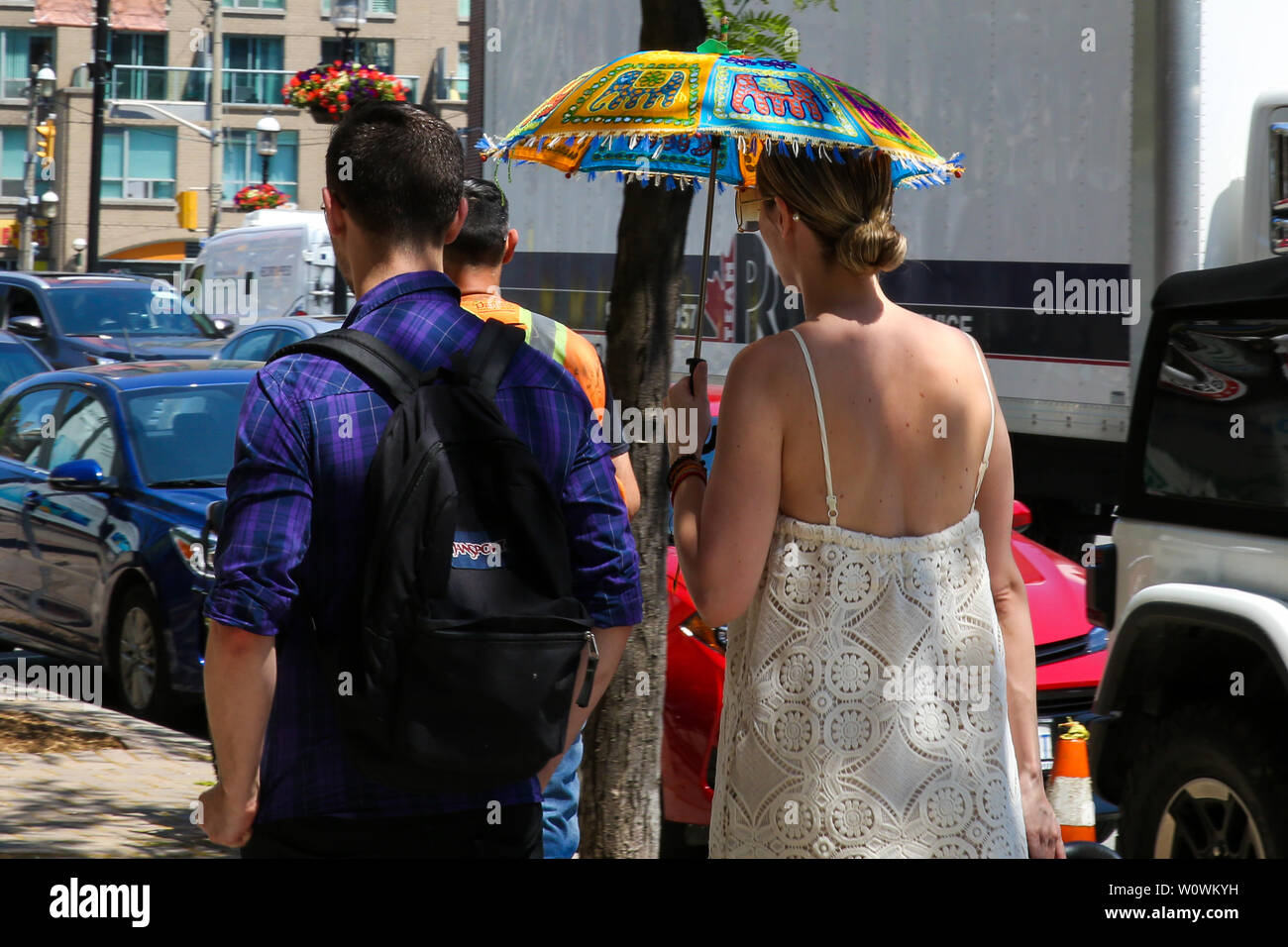 Toronto, Canada. 27 Juin, 2019. Une femme tient un parapluie coloré au  cours d'une journée ensoleillée et chaude à Toronto.La température devrait  monter à 30 degrés celsius plus tard cette semaine. Credit :