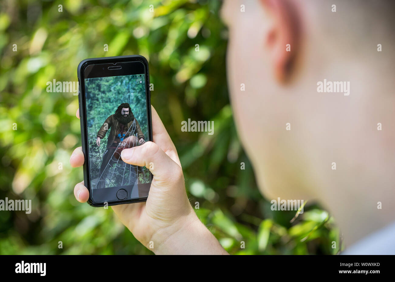 Un jeune garçon jouant les nouveaux assistants de Harry Potter s'unir App sur son iPhone dans le parc Banque D'Images