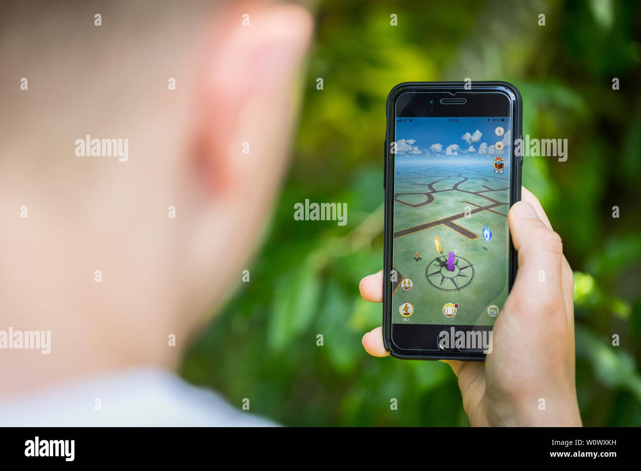 Un jeune garçon jouant les nouveaux assistants de Harry Potter s'unir App sur son iPhone dans le parc Banque D'Images