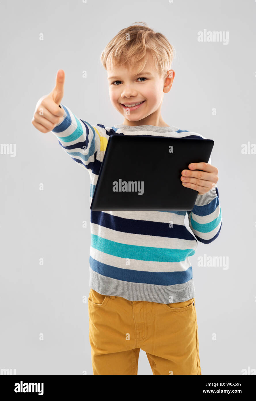 Smiling boy with tablet computer showing Thumbs up Banque D'Images