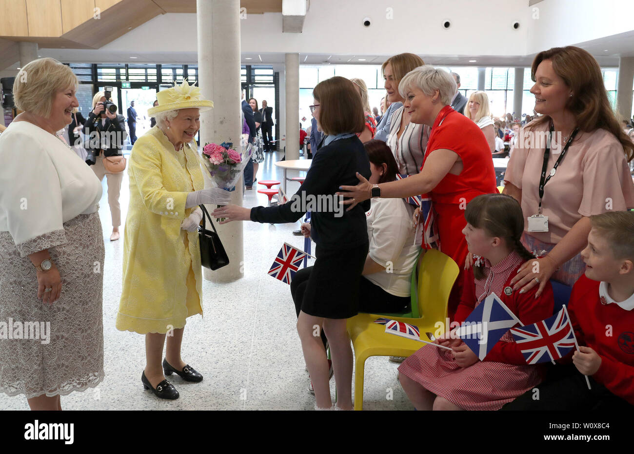 La reine Elizabeth II reçoit un bouquet de fleurs à partir de Ciara Martin lors d'une visite à Greenfaulds High School, à l'ouest de Lokeren. Banque D'Images