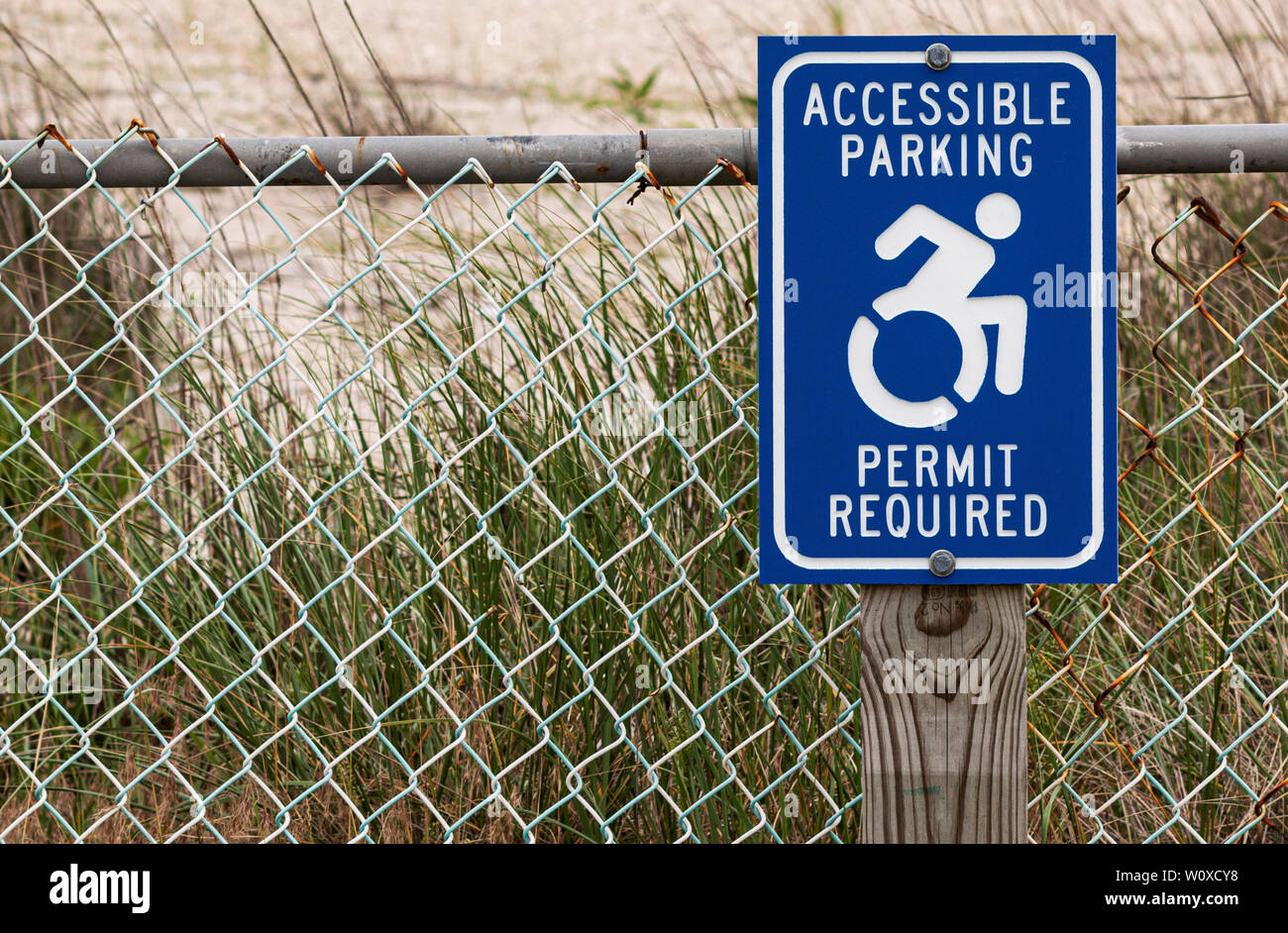 Permis de stationnement accessible panneau requis sur un poteau de bois en face des dunes pour les personnes handicapées de se garer à la plage. Banque D'Images