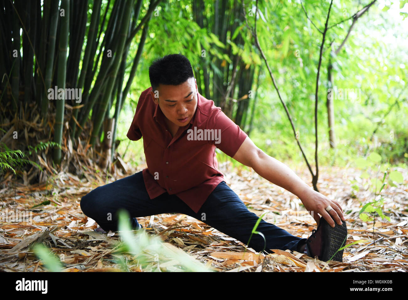 (190628) -- CHONGQING, 28 juin 2019 (Xinhua) -- Liu Yi prend de l'exercice dans une forêt de bambous dans Nanchuan District, Chongqing, du sud-ouest de la Chine, 27 juin 2019. Malgré la perte de son bras droit dans un accident à l'âge de neuf ans, 44 ans, Liu Yi n'a jamais baissé la tête vers le destin. Après l'obtention du diplôme d'une école de formation professionnelle en 1994, il a essayé de nombreux emplois comme lave-vaisselle, fruits concessionnaire et mineur de charbon. Depuis 2010, il a décidé de démarrer sa propre entreprise à sa ville natale en organisant les villageois à planter des racines de bambou et d'élever des poulets. Ses efforts ont porté fruit. En 2016, toutefois, Liu Yi s'int Banque D'Images