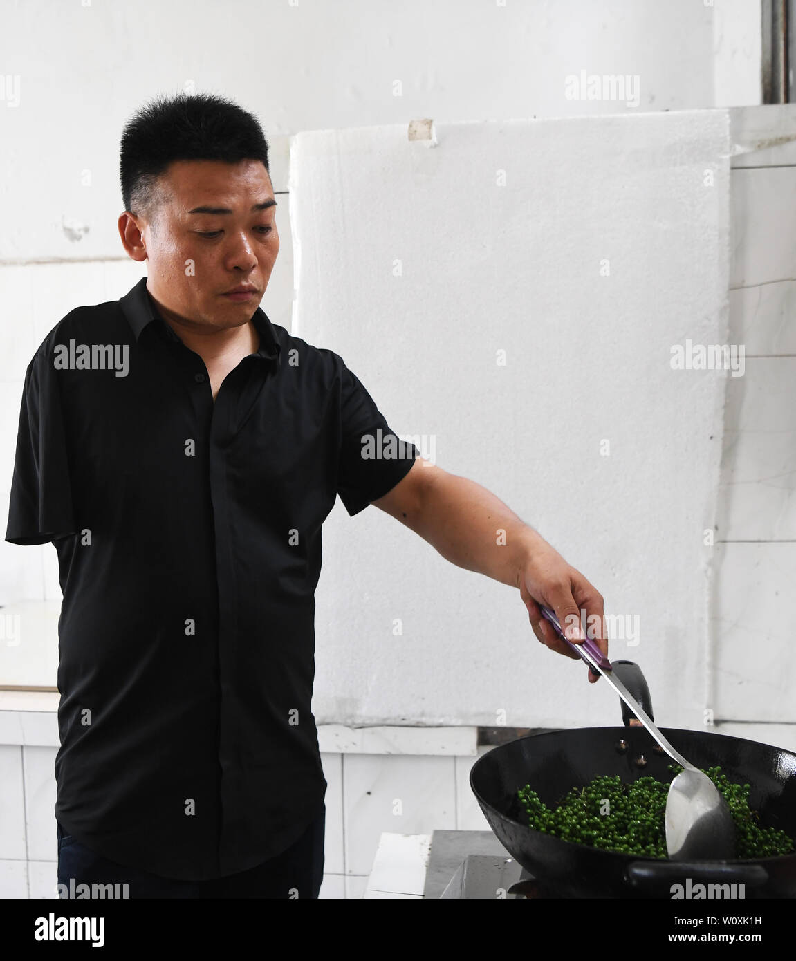 (190628) -- CHONGQING, 28 juin 2019 (Xinhua) -- Liu Yi fait poivre huile dans Nanchuan District, Chongqing, du sud-ouest de la Chine, 27 juin 2019. Malgré la perte de son bras droit dans un accident à l'âge de neuf ans, 44 ans, Liu Yi n'a jamais baissé la tête vers le destin. Après l'obtention du diplôme d'une école de formation professionnelle en 1994, il a essayé de nombreux emplois comme lave-vaisselle, fruits concessionnaire et mineur de charbon. Depuis 2010, il a décidé de démarrer sa propre entreprise à sa ville natale en organisant les villageois à planter des racines de bambou et d'élever des poulets. Ses efforts ont porté fruit. En 2016, toutefois, Liu Yi s'est intéressé à planti Banque D'Images