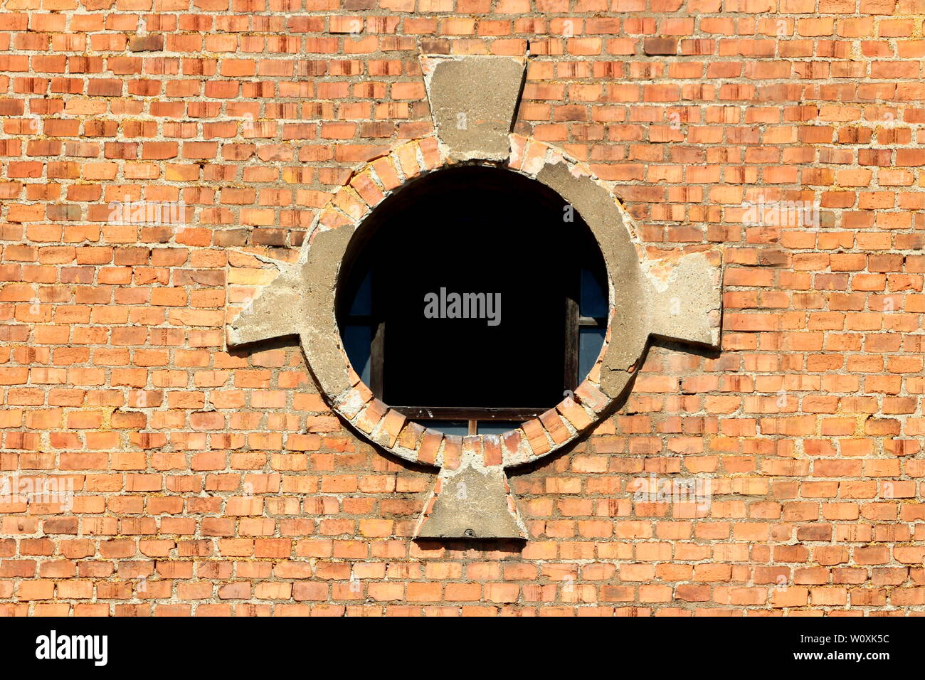 Ouverture de fenêtre ronde avec le verre brisé et partiellement en briques rouges décoratifs minéral cadre sur la construction de complexes industriels abandonnés ancienne Banque D'Images