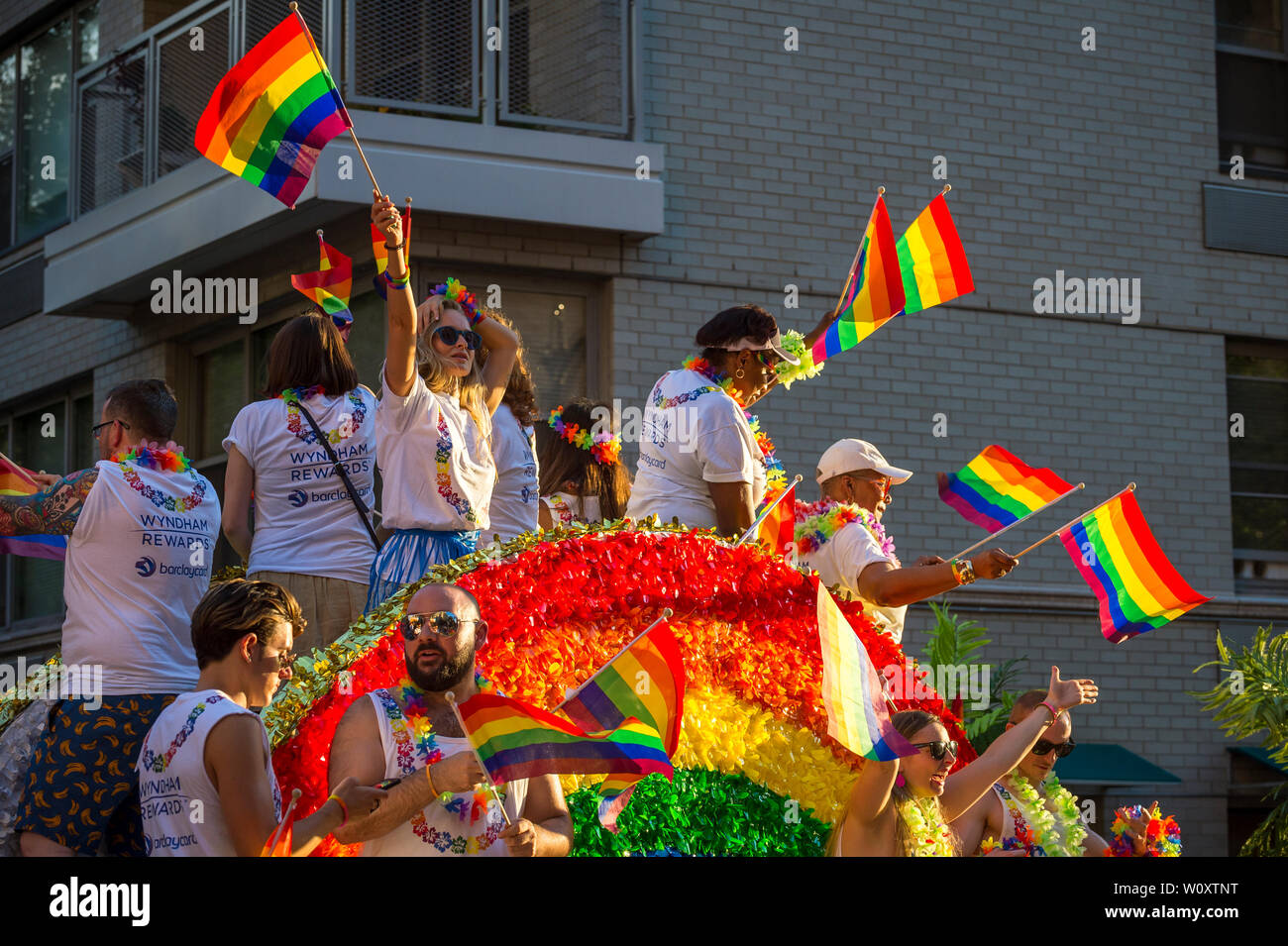 NEW YORK - 25 juin 2017 : Les participants port shirts sponsorisé par les marques Wyndham et Barclays agitent des drapeaux sur un flotteur dans la parade de la gay pride. Banque D'Images