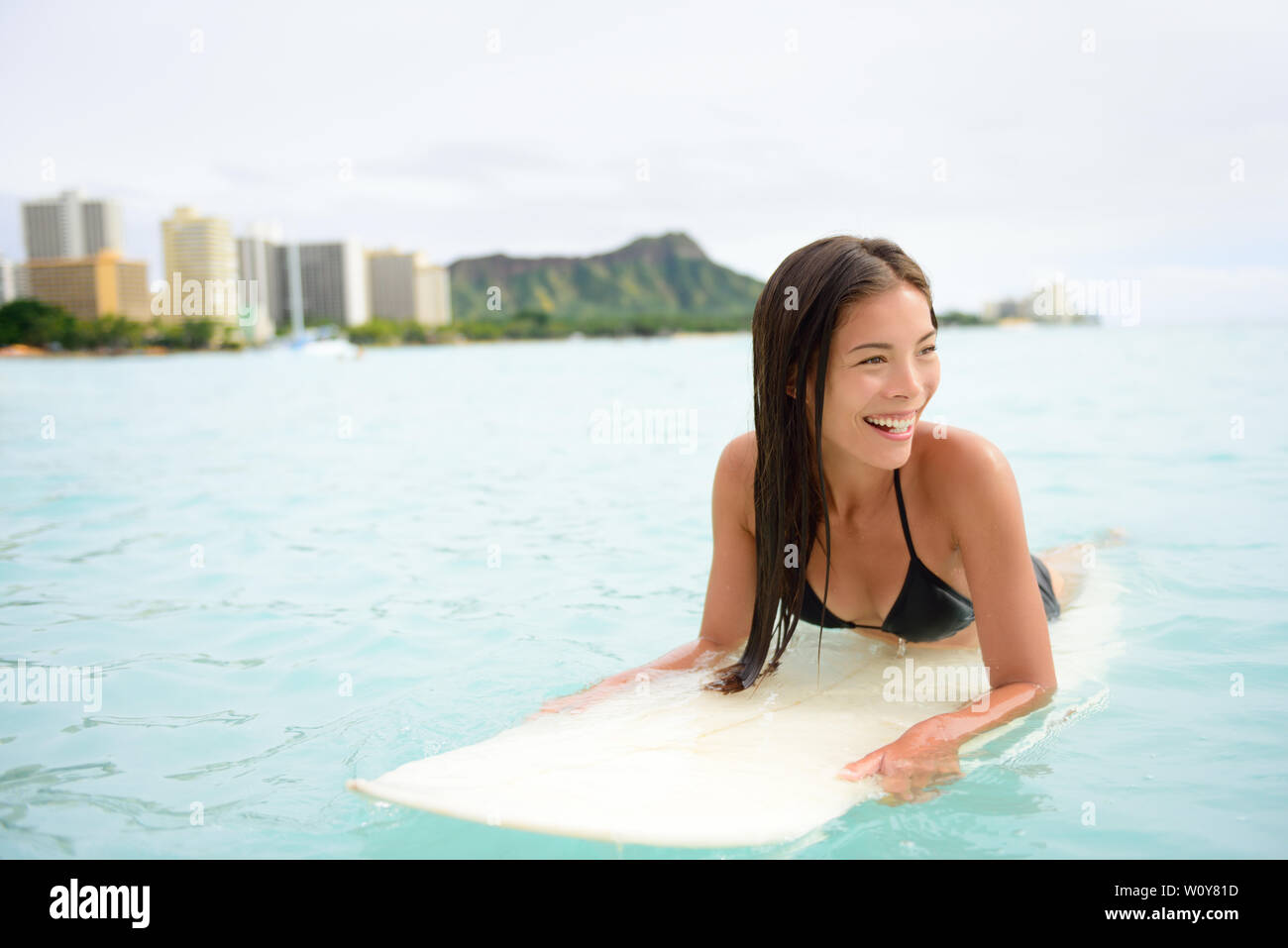 Femme surfeur surf sur la plage de Waikiki, Oahu, Hawaii. Femme fille bikini sur surfboard smiling heureux de vivre une vie active saine sur plage hawaïenne. Modèle Caucasien Asiatique. Banque D'Images
