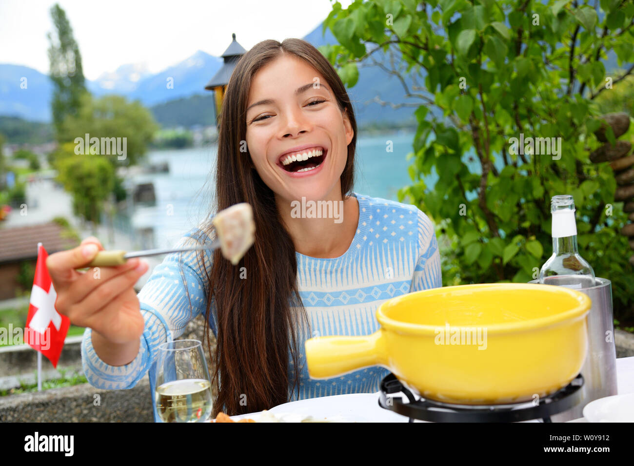 Fondue au fromage suisse. Femme en riant montrant et manger du pain avec du fromage fondu. Des plats traditionnels de la Suisse. Les gens s'amusant par le lac dans les Alpes sur les voyages en Europe. Banque D'Images