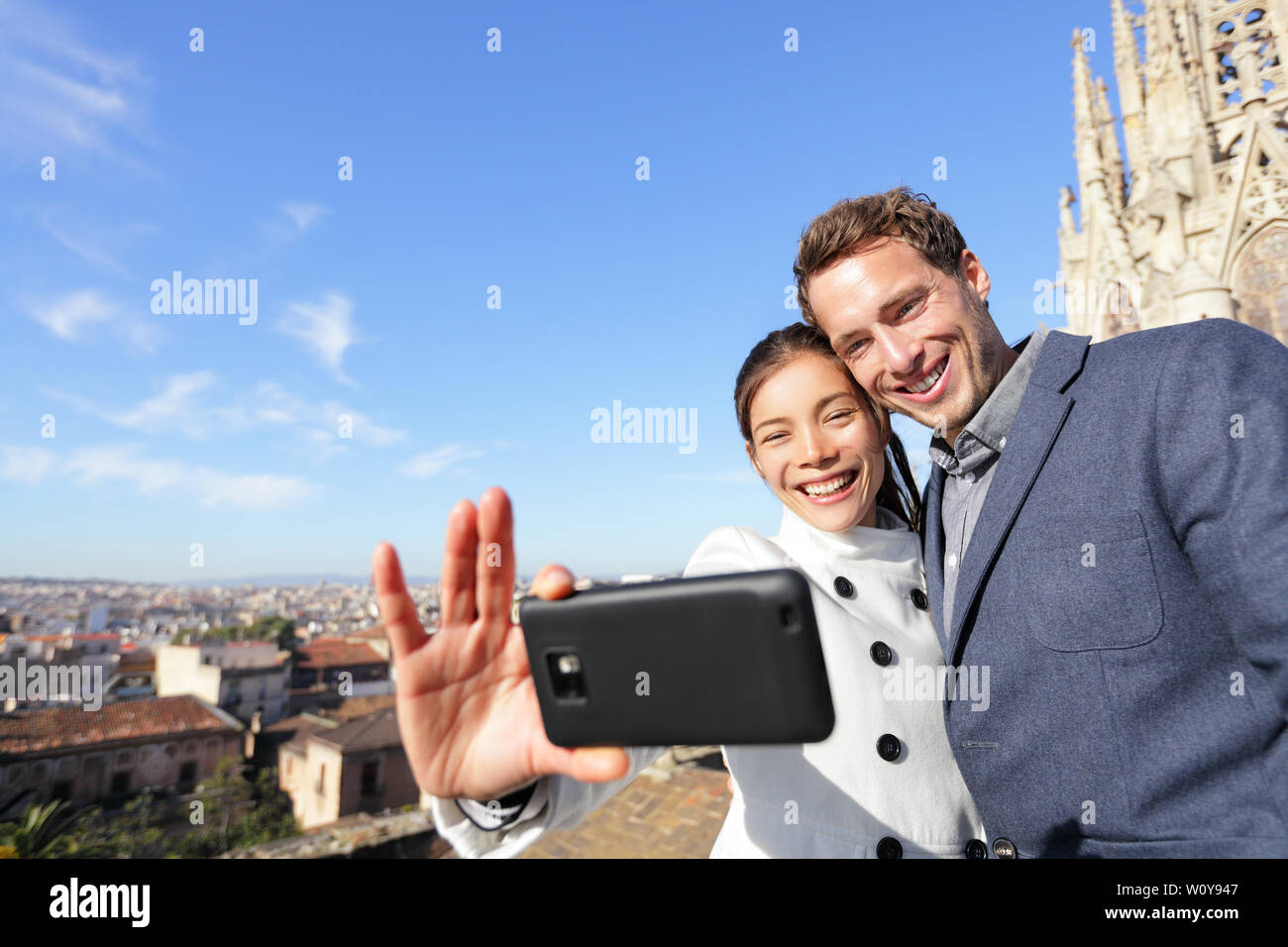 Jeune couple urbain sur le voyage à Barcelone en tenant self portrait photograph selfies avec smart phone appareil photo. Heureux jeune homme et femme en face de l'église de Barcelone, Espagne. Banque D'Images