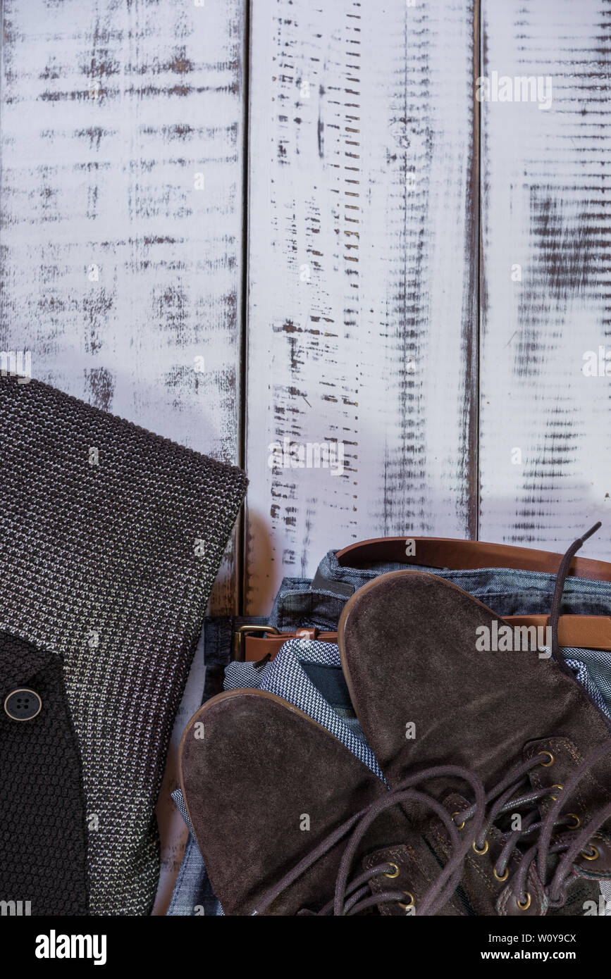 Jean robe avec ceinture brune,polo gris, marron chaussures et pull marron sur une table en bois blanc Banque D'Images