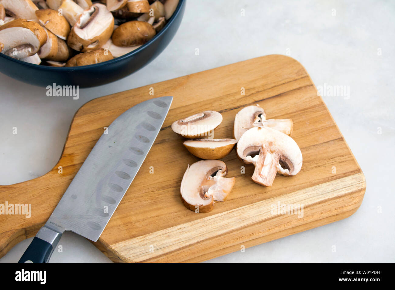 Champignons Cremini trancher sur une planche à découper en bois Banque D'Images