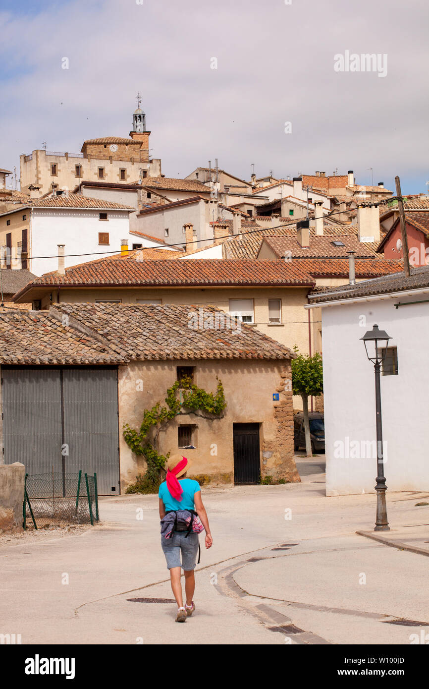 Femme pèlerine marchant dans la campagne espagnole sur le Camino de Santiago le chemin de St James approchant le village de Cirauqui Navarra Espagne Banque D'Images