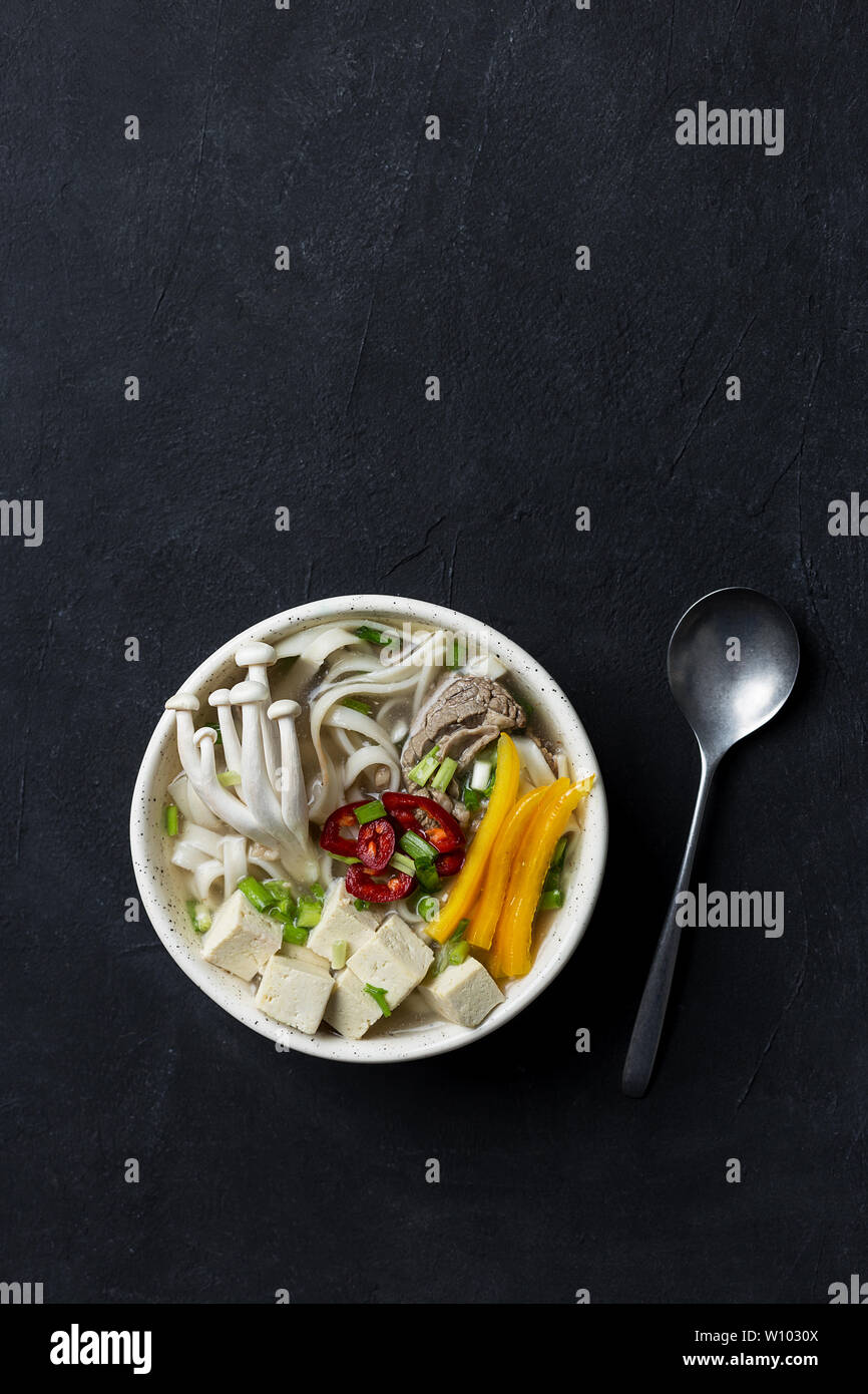 Soupe de nouilles aux champignons et légumes avec cuillère sur fond sombre.Top voir télévision lay, copie espace pour le texte. Concept de la nourriture japonaise Banque D'Images Soupe de nouilles aux champignons et légumes avec cuillère sur fond sombre.Top voir télévision lay, copie espace pour le texte. Concept de la nourriture japonaise Banque D'Images