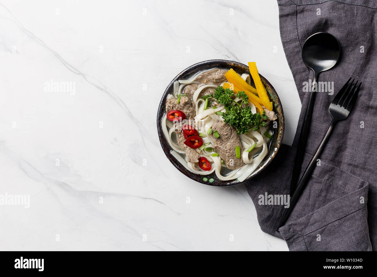 Soupe de nouilles asiatiques, avec la viande et les légumes dans un bol avec de la vaisselle et serviettes sur fond blanc. Vue supérieure horizontale, l'espace libre pour le texte Banque D'Images Soupe de nouilles asiatiques, avec la viande et les légumes dans un bol avec de la vaisselle et serviettes sur fond blanc. Vue supérieure horizontale, l'espace libre pour le texte Banque D'Images