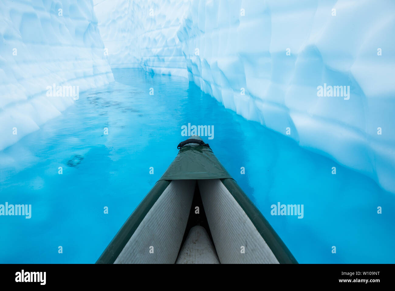 Canoë à travers une crevasse remplie d'eau de l'eau glaciaire d'un bleu profond sur le dessus de la Matanuska Glacier en Alaska. La piscine ou le lac bleu glacier avec w Banque D'Images