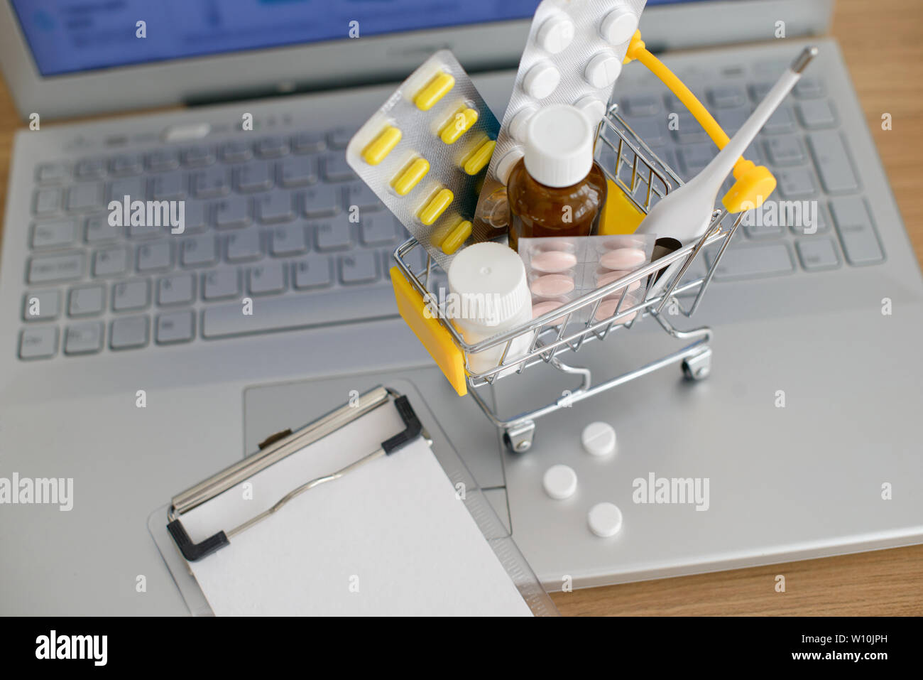 Panier jouet avec des médicaments et du papier remarque devant un écran d'ordinateur portable avec pharmacie site web sur elle. Comprimés, blisters, flacons médical, therm Banque D'Images