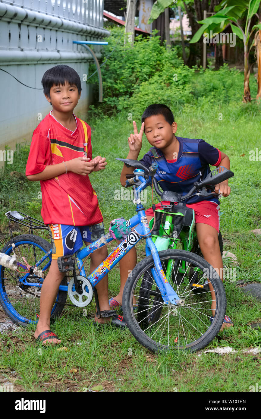 Deux garçons avec leurs bicyclettes dans Nonthaburi, Thaïlande, un clignotant l'omniprésent V sign Banque D'Images