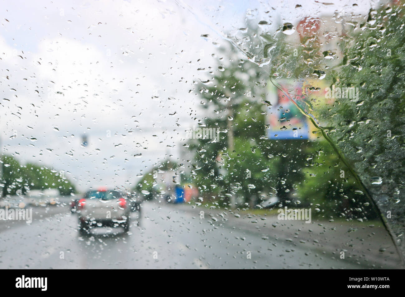 Gouttes de pluie sur le pare-brise de la voiture. Focus sélectif. La vue depuis la fenêtre de voiture sur la route. Mauvaise visibilité. Banque D'Images