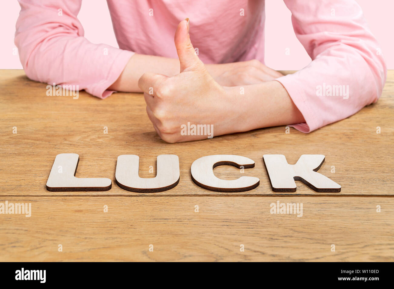 Mot chance énoncés dans les lettres sur une vieille table en bois, derrière lequel une femme assise et montre un Thumbs up Banque D'Images