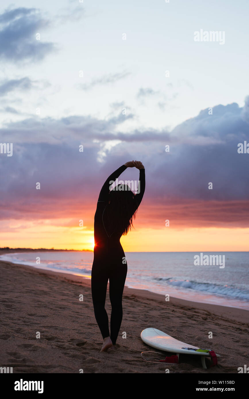 Jeune femme se réchauffer sur la plage avant de surf Banque D'Images