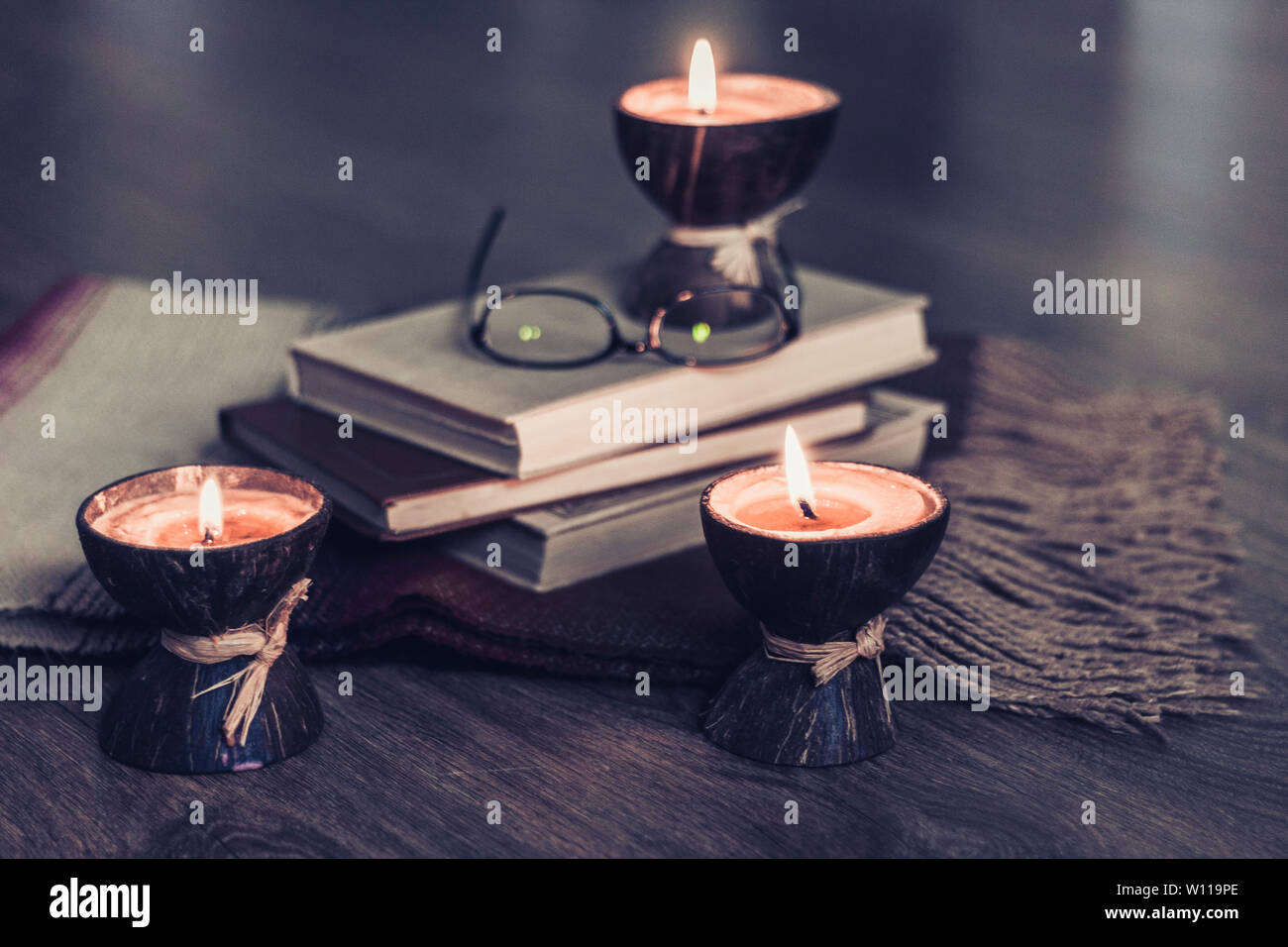 Spa aroma candles burning en coque de noix de coco, plaid, des verres et des livres, l'arrière-plan intérieur cosy home Banque D'Images