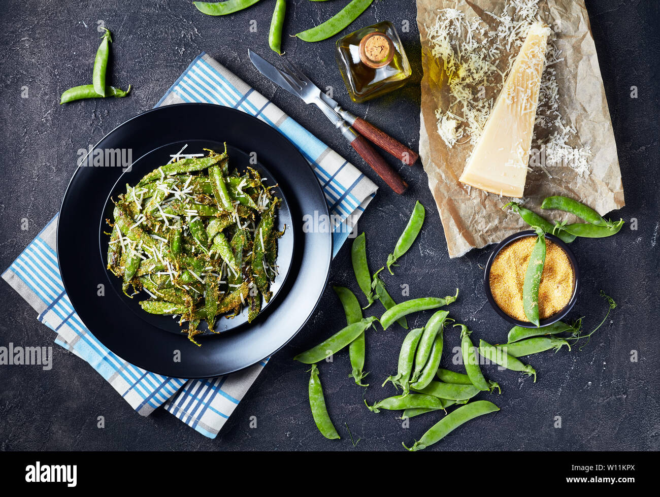 Vue de dessus de la polenta rôtie croustillante au parmesan et petits pois pané servi sur un plateau. Ingrédients sur une table en béton, vue horizontale à partir de ci-dessus, Banque D'Images