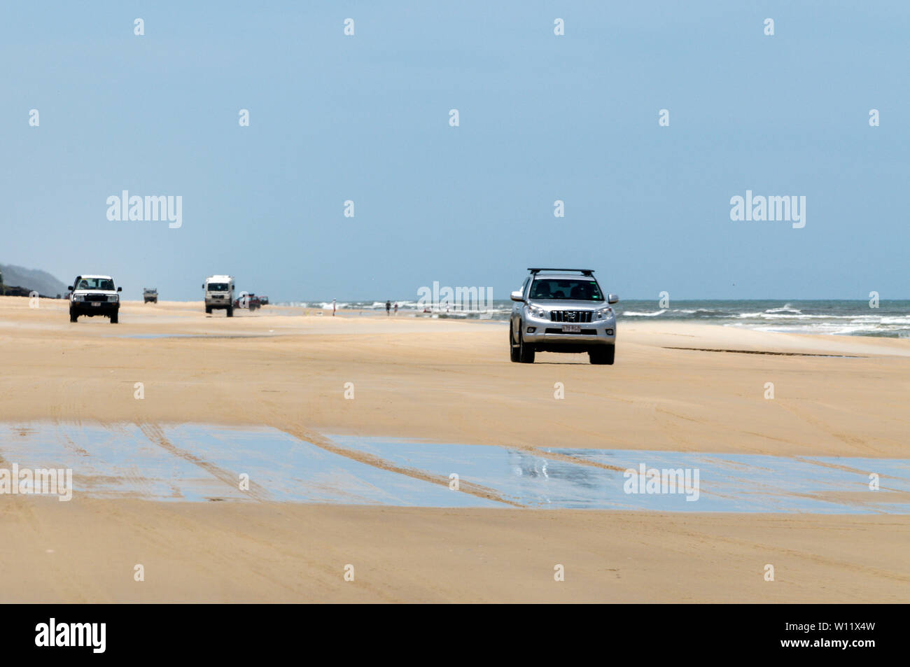 Un convoi de 4x4 sur les deux voies de l'Autoroute 75 km longue plage de sable fin face à l'océan Pacifique Sud sur Fraser Island, Queensland, Australie. La plage hi Banque D'Images