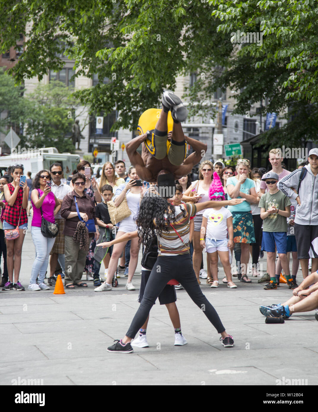 Acrobates de divertir une foule importante par City Hall Park le long de Park Row dans le lower Manhattan. Banque D'Images